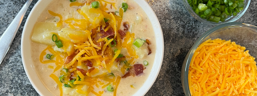 potato soup in a bowl topped with bacon, chives, and cheddar cheese